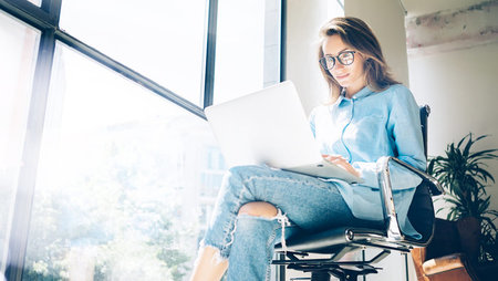 young woman sitting in office chair and working on laptop