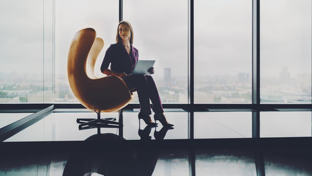 Young business woman sitting in a curved armchair in a skyscraper office