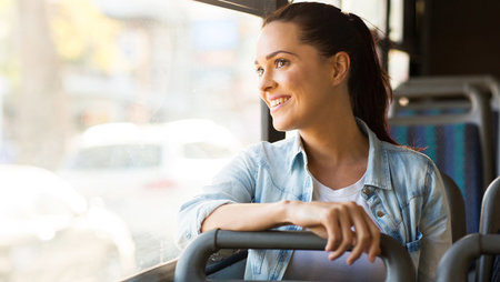 A smiling young woman looking out the bus window