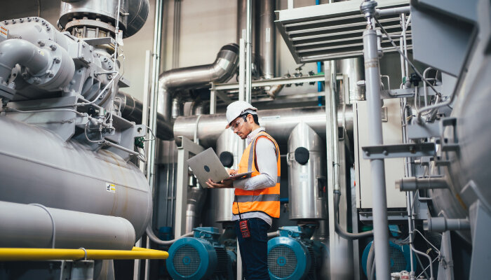 A male engineer holding a laptop in a factory