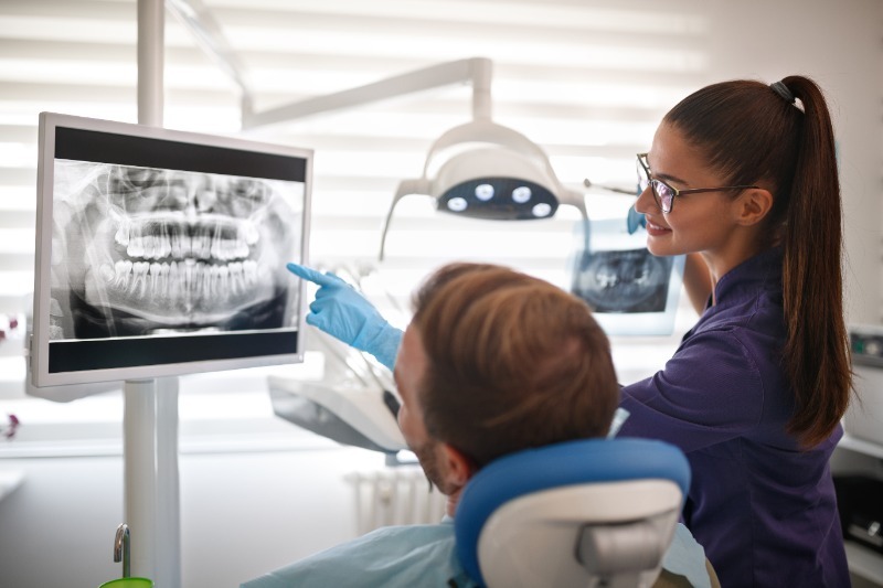 Orthodontist with a patient showing them their dental scans